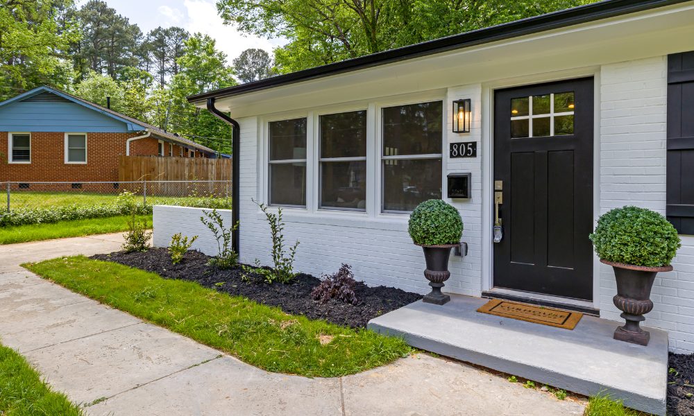 white brick bungalow with a new black fiberglass front door