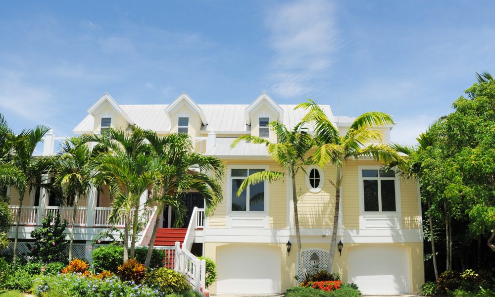 yellow coastal home with palm trees in the courtyard