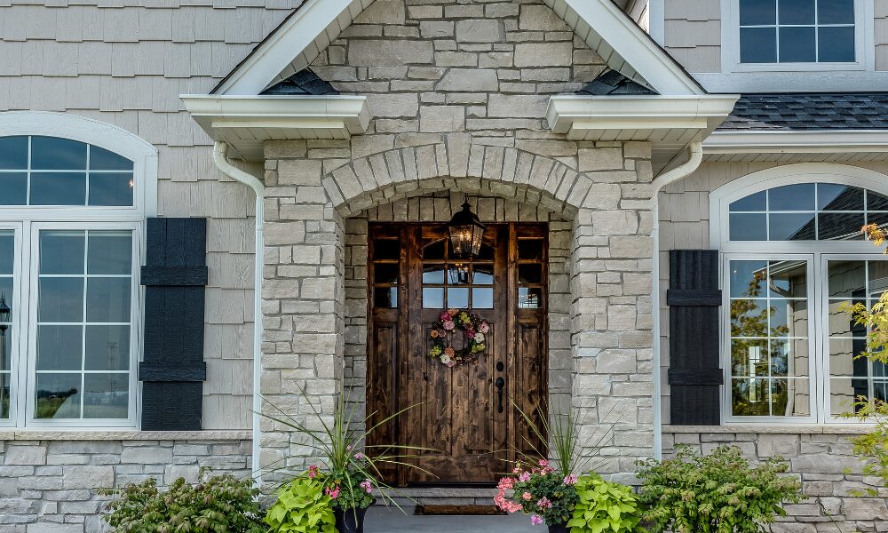 Greige home with stone and siding and a wood front door with sidelites